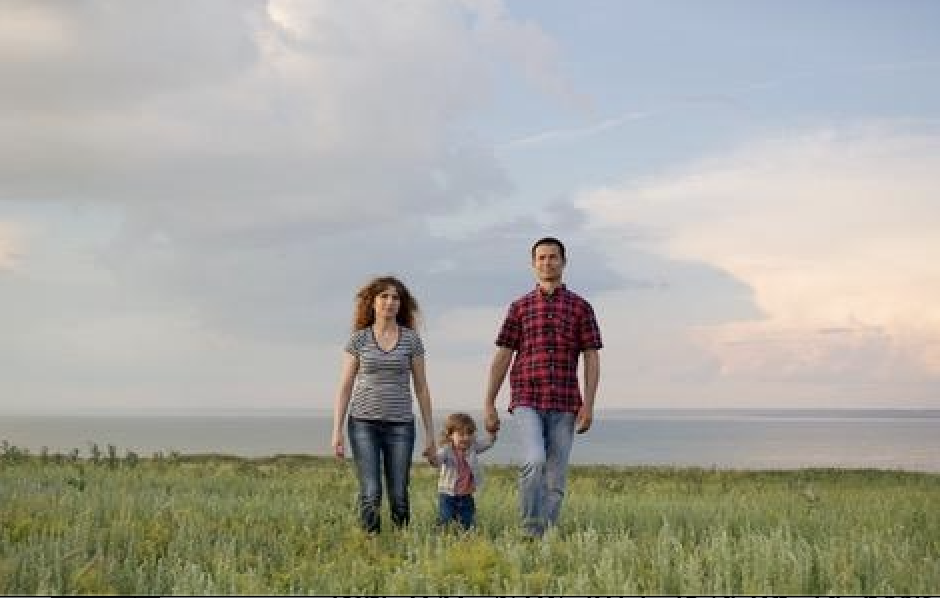 Familie geht gemeinsam über eine Wiese am Meer